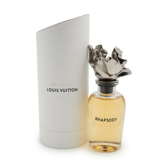 Louis Vuitton Rhapsody perfume bottle with amber liquid and sculptural silver cap next to its white cylindrical box on a white background.